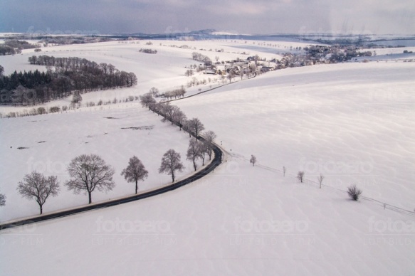 Schneeverwehungen auf dem Feld, WÃ¤lder und ein Dorf